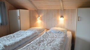 Ein Zimmer mit zwei Einzelbetten, Holzwänden und zwei Wandleuchten.