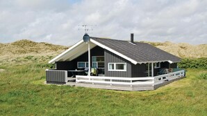 Ein modernes Haus mit geneigtem Dach, einer überdachten Terrasse und einer Satellitenschüssel.
