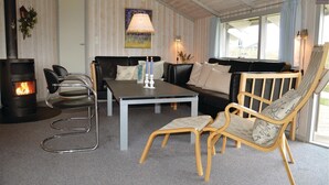 Ein gemütliches Wohnzimmer mit Kamin, einer Couch, einem Couchtisch und einem Sessel.
