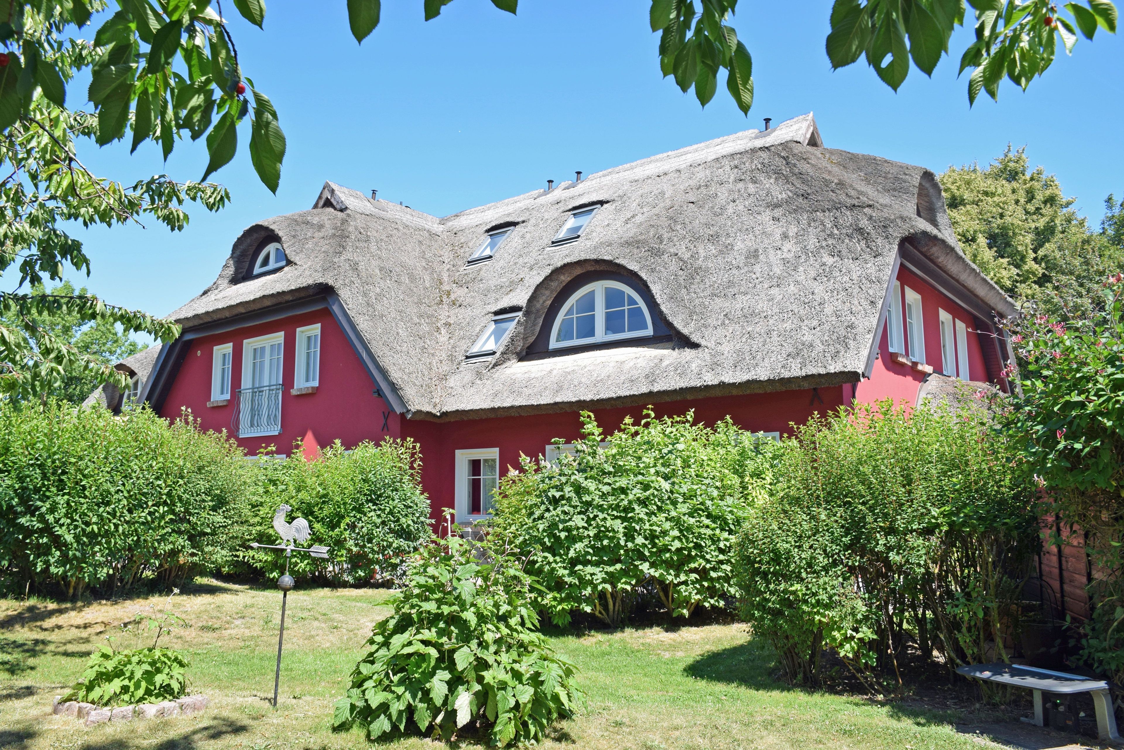 A red building with a thatched roof, surrounded by greenery.