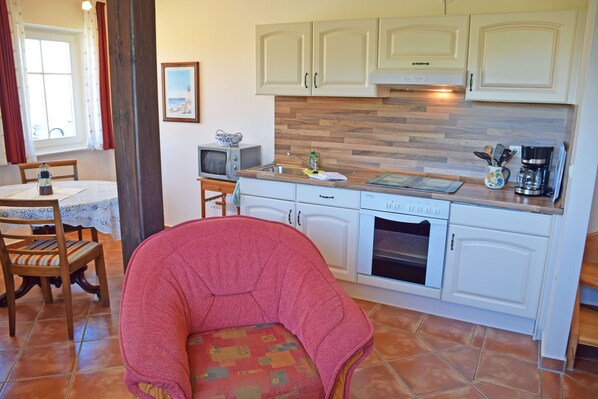 A kitchen with white cabinets, a wooden countertop, a microwave, and a coffee maker.
