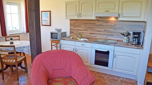 Cocina con armarios blancos, encimera de madera, microondas y cafetera.