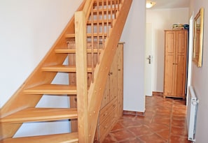 Una escalera de madera que conduce a una plataforma con un armario y una puerta al fondo.