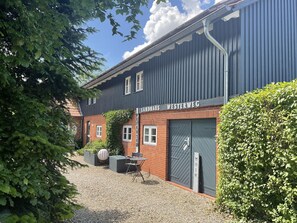 A building with a sign reading "LANDHAUS WESTERWEG" and a gravel driveway.