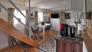 Ett kompakt bostadsutrymme med ett litet kök, en matplats och en trappa.