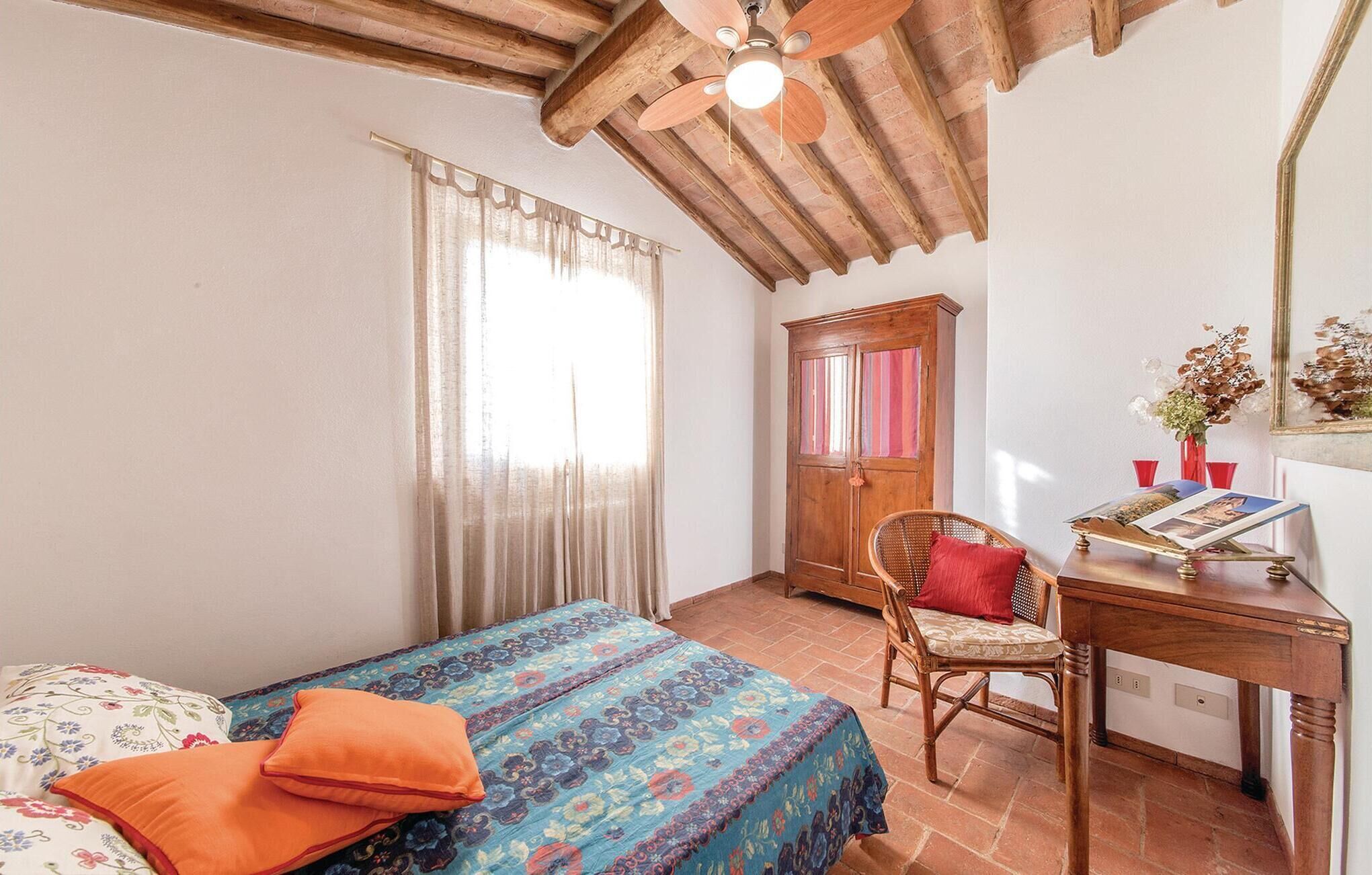 A bedroom with a bed, a desk, a chair, and a wardrobe.