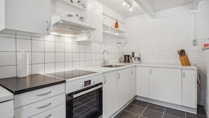 A modern kitchen with white cabinetry, a black oven, a sink, and a coffee maker. - Awesome apartment in Rømø with WiFi (Rømø)