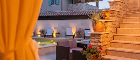 Un área de piscina con sillones de descanso y una escalera de piedra.