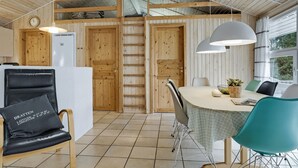 A cozy room with a wooden ceiling, a dining table with chairs, a black leather chair with a pillow, and a window with curtains. - Nice home in Jerup with kitchen (Jerup)