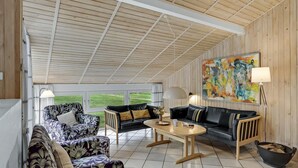 A covered outdoor living area with a wooden ceiling, two sofas, a table, and a painting on the wall. - Nice home in Jerup with kitchen (Jerup)