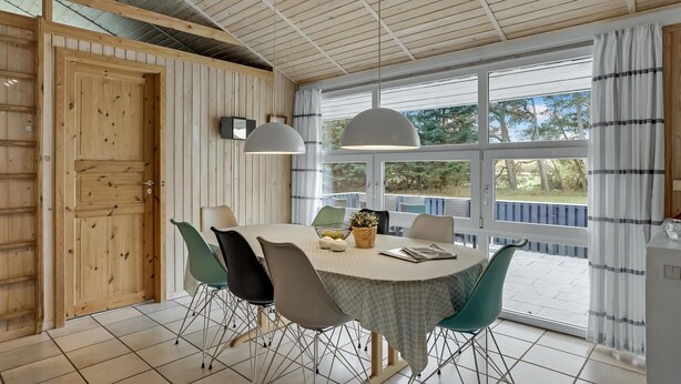 A dining area with a round table, chairs, pendant lights, and a view through large windows. - Nice home in Jerup with kitchen (Jerup)