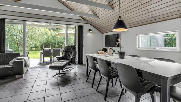 A modern kitchen with a large dining table, black chairs, and a pendant light.