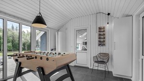 A modern room with a foosball table, a wicker chair, and a large window offering a view of the outdoors.
