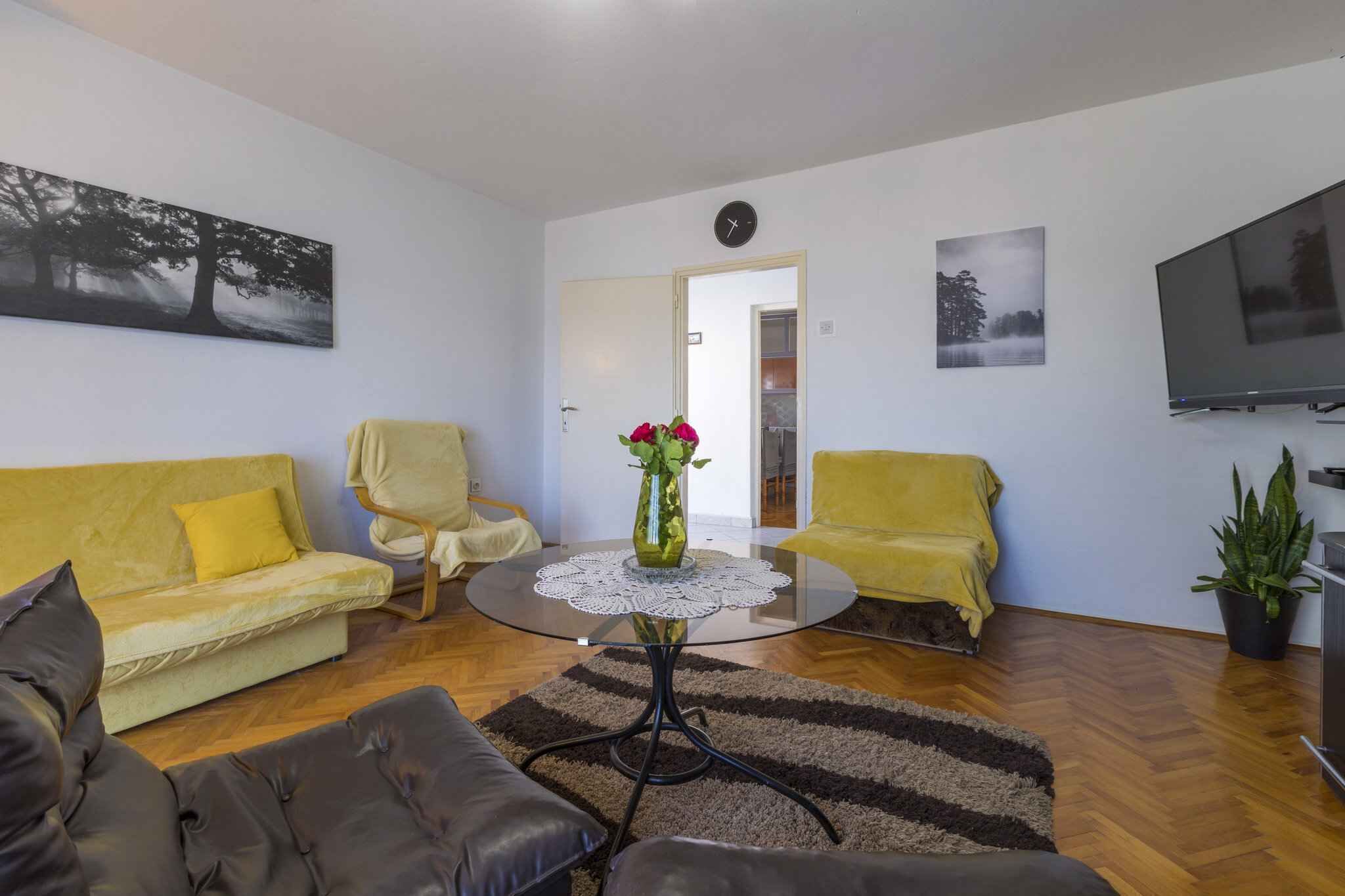 Un salon avec un canapé, des fauteuils, une table basse et un téléviseur.