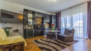 Een moderne woonkamer met een bank, een salontafel en een aan de muur bevestigde televisie.