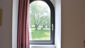 A window with a black frame and a view of a tree and grass outside. - Amazing home in Auxais with WiFi (Auxais)