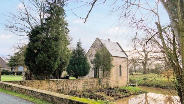 A stone church with a small pond in front, surrounded by trees and a grassy area. - Amazing home in Auxais with WiFi (Auxais)