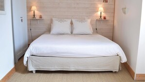 A bedroom with a bed, two bedside tables with lamps, a small picture on the wall, and a door. - Amazing home in Auxais with WiFi (Auxais)