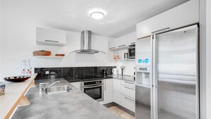 Uma cozinha moderna com geladeira de aço inoxidável, forno embutido e micro-ondas.