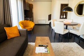 Un salon moderne comprenant un canapé, un fauteuil, une table basse et un coin repas.