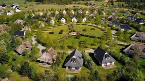 Ein Dorf mit traditionellen Häusern, einer zentralen Grünfläche und einem Gebäude mit Strohdach.