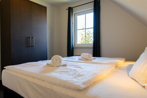 Une chambre avec deux lits, une fenêtre avec des rideaux et une armoire.