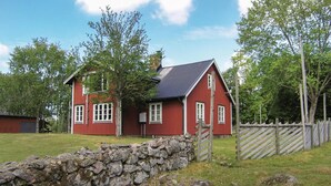 A red house with a stone wall in front, surrounded by trees and a wooden fence. - Stunning home in Lidhult with WiFi (Lidhult)