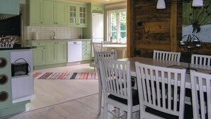 A kitchen with green cabinets, a white dishwasher, and a dining area with white chairs and a table. - Stunning home in Lidhult with WiFi (Lidhult)