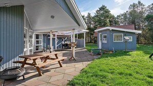 Ett hus med en inglasad uteplats, ett litet förråd och en grill.