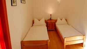 A small, clean room with two wooden beds, a nightstand, and a wall-mounted light. - Apartment 2 - Rügen apartment 106 (Wiek)