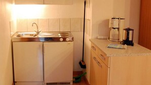 A compact kitchen with a sink, stove, and coffee maker. - Apartment 2 - Rügen apartment 106 (Wiek)
