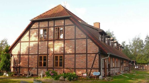 A traditional half-timbered house with a steeply pitched roof, large windows, and a well-maintained garden. - Apartment 2 - Rügen apartment 106 (Wiek)