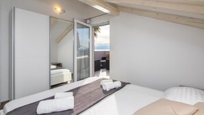 A modern bedroom with a large bed, a glass door leading to an outdoor area, and a wooden ceiling.