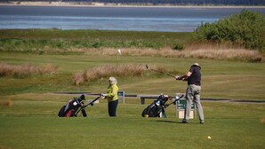 Un campo de golf con un cuerpo de agua al fondo.