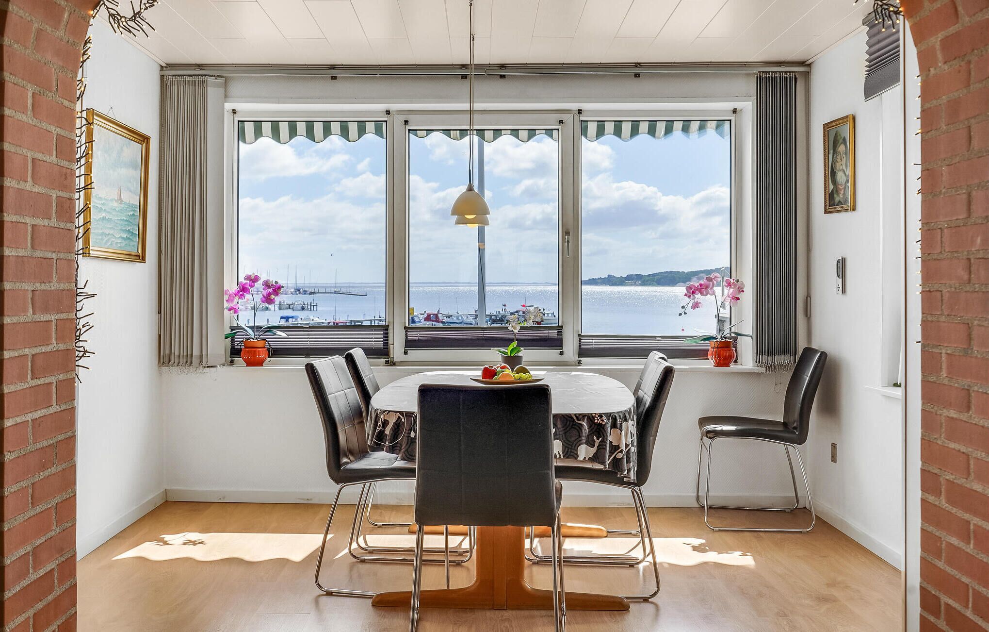Un comedor con una mesa redonda, cuatro sillas y vista al mar a través de amplios ventanales.