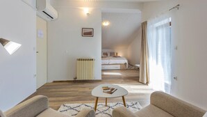 Un salon moderne et bien éclairé, avec un canapé, une table basse et une vue sur une chambre à coucher.