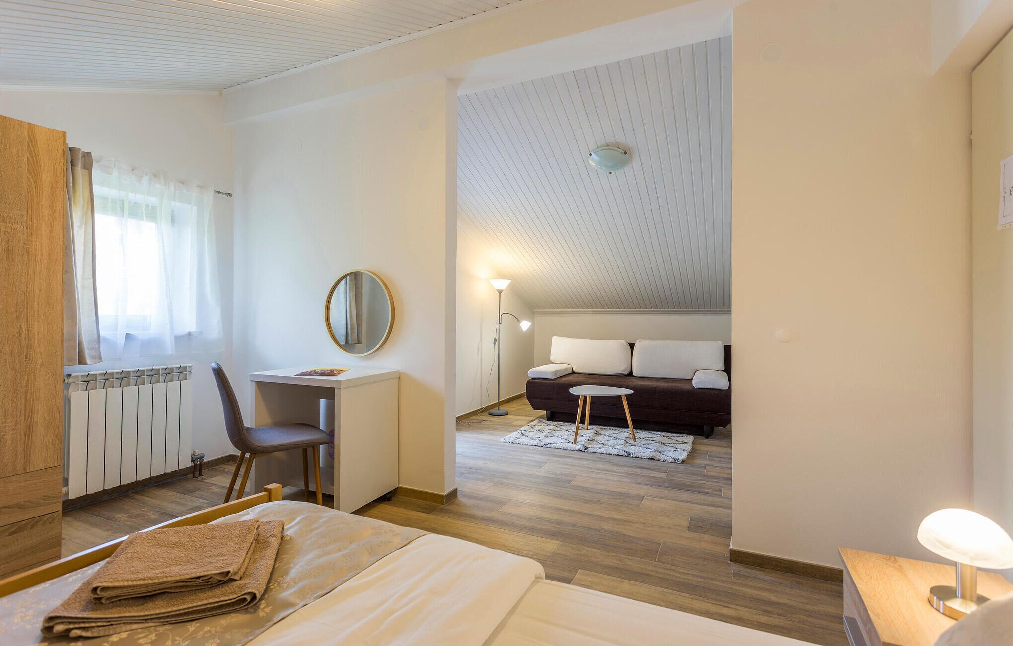 A hotel room with a bed, a desk, a chair, a sofa, and a small table.
