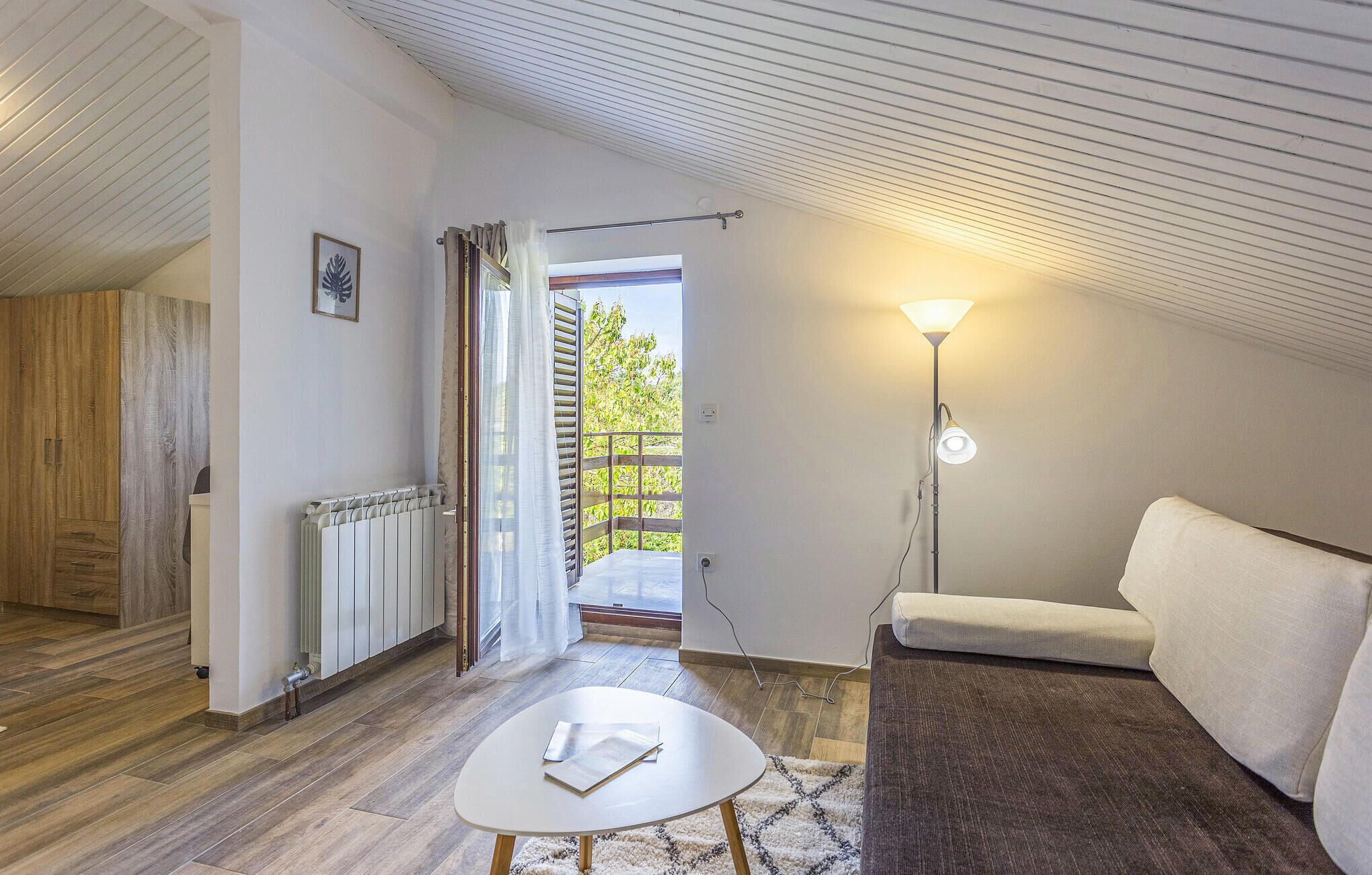 A cozy room with a white sofa, a small round table, a radiator, and a floor lamp.