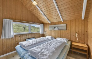 A wooden-paneled room with a bed, a window, and a painting. - Beach front home in Hvide Sande (Hvide Sande)
