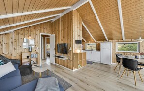 A cozy cabin interior with a living room, dining area, kitchen, and a bedroom. - Beach front home in Hvide Sande (Hvide Sande)