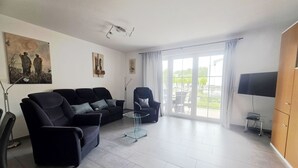 Una sala moderna con sofá, sillón y televisor.