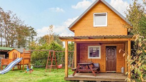 A wooden cabin with a porch, a small deck, and a slide in the yard. - 2 bedroom pet friendly home in Karwienskie Blota (Karwienskie Blota)