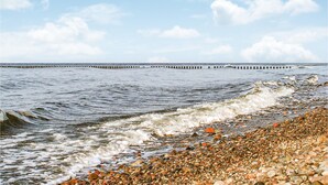 A beach with pebbles and waves, a wooden pier in the distance, and a clear sky. - 2 bedroom pet friendly home in Karwienskie Blota (Karwienskie Blota)