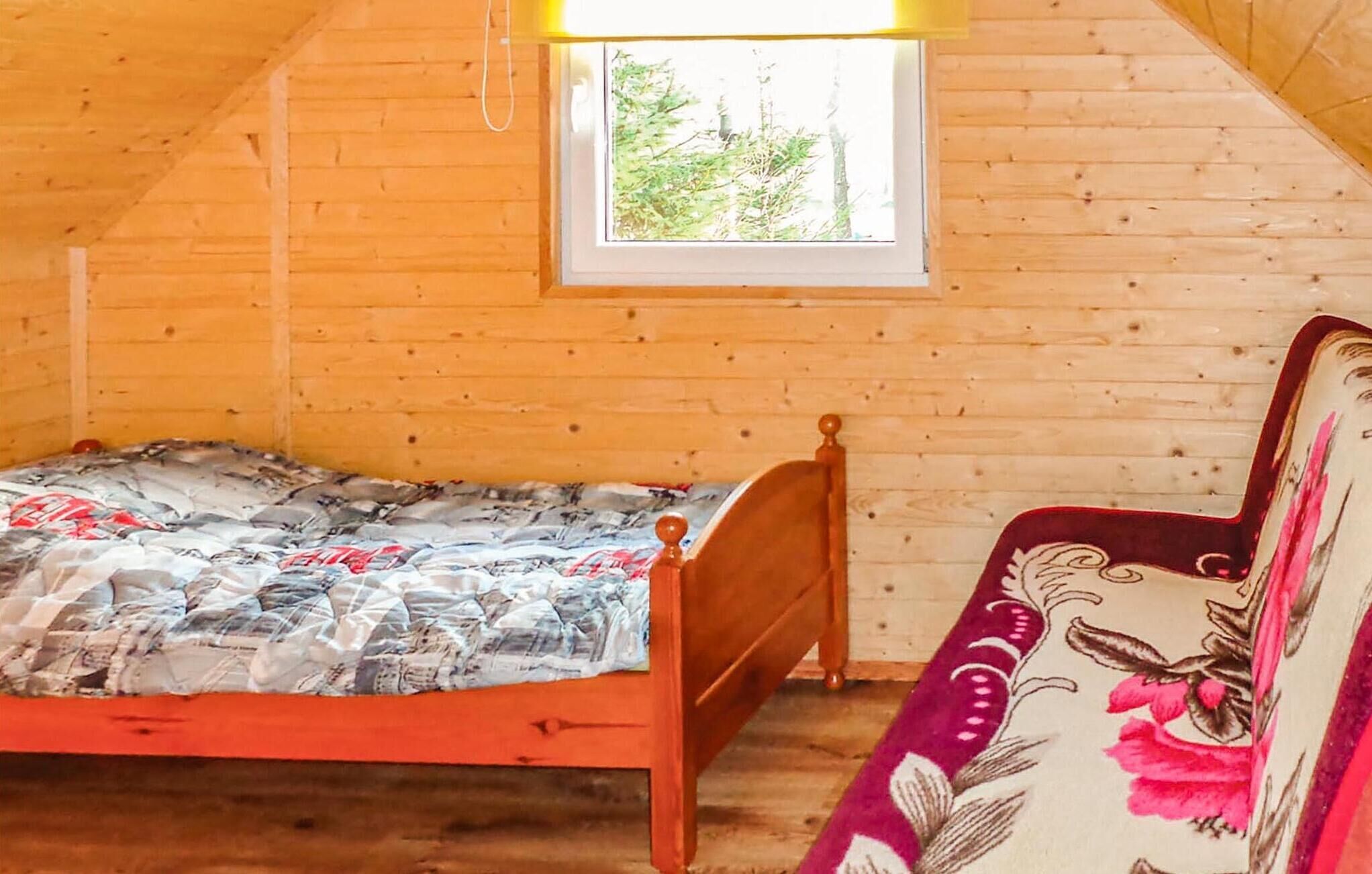 A wooden room with a bed, a window, and a sofa.