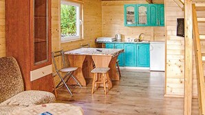 A wooden cabin interior with a dining table, chairs, a kitchen with turquoise cabinets, and a window. - 2 bedroom pet friendly home in Karwienskie Blota (Karwienskie Blota)
