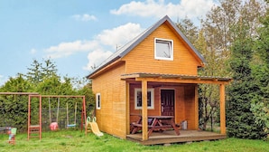 A wooden cabin with a porch, a play area with a swing set, and a slide. - 2 bedroom pet friendly home in Karwienskie Blota (Karwienskie Blota)