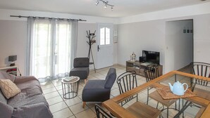A living room with a sofa, a dining table with chairs, a TV, and a lamp. - 3 bedroom nice home in Saint-Thomé (Saint-Thomé)