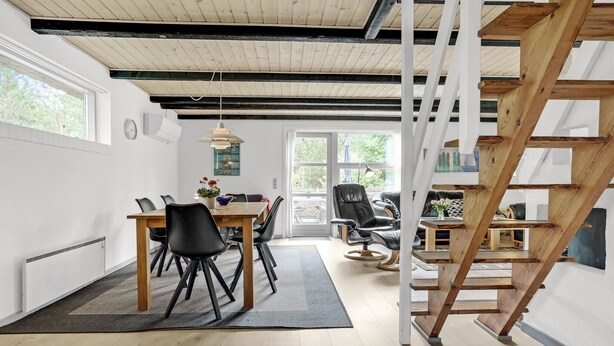 Een modern interieur met een eethoek, een trap en uitzicht door een glazen deur.
