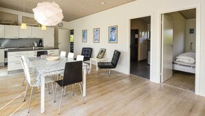 A modern kitchen with white cabinets, a dining area with a marble table, and a living space with a bed and artwork. - Beautiful home in Haderslev with WiFi (Haderslev)