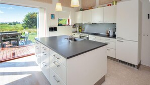 A modern kitchen with white cabinets, a large island with a sink, and a view of the outdoors. - Beautiful home in Haderslev with WiFi (Haderslev)
